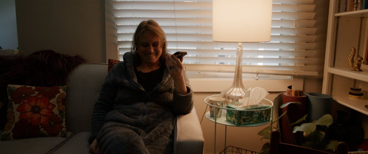 Abbey on her couch, smiling at her phone.
